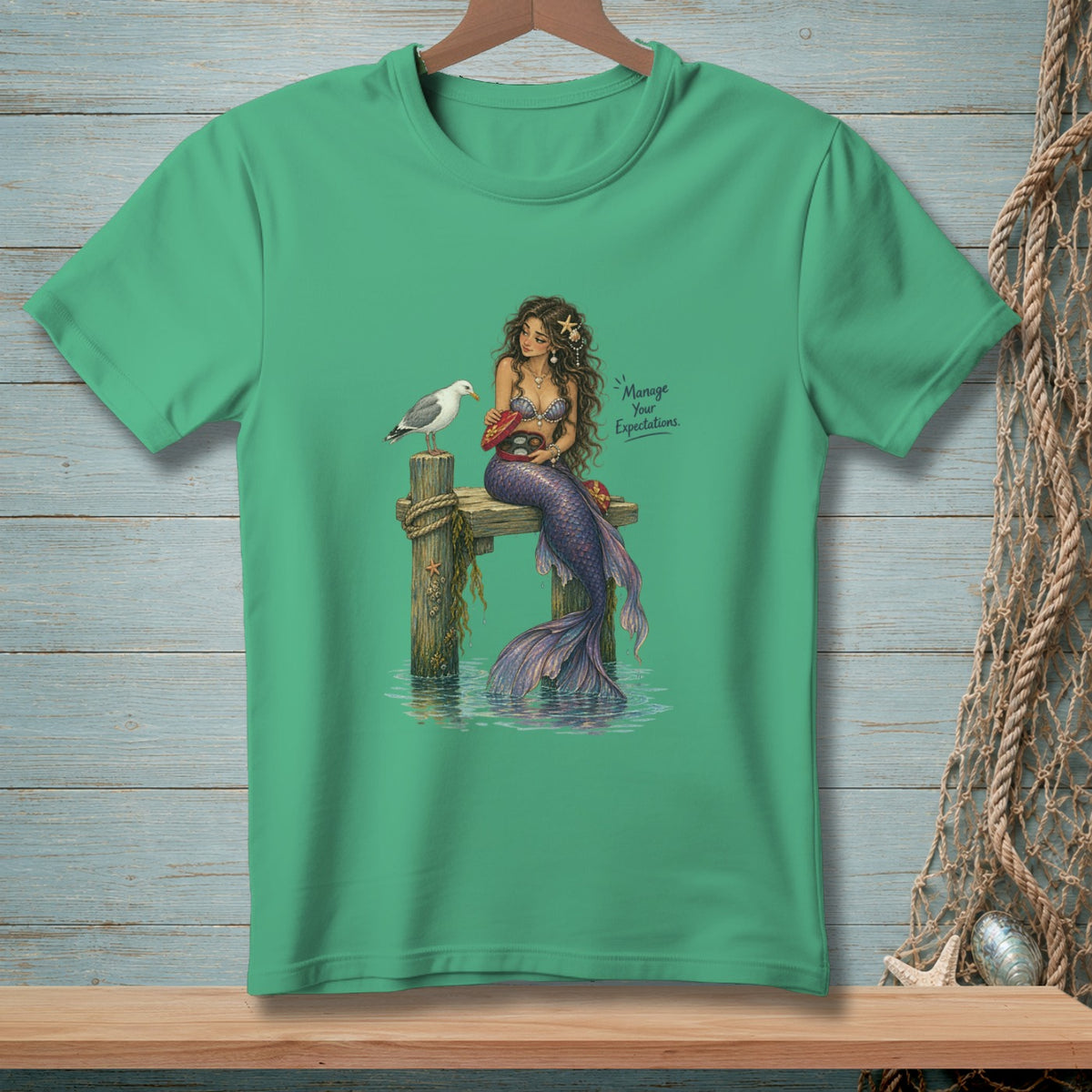 Mermaid sitting on a dock with a seagull and a box of chocolates.