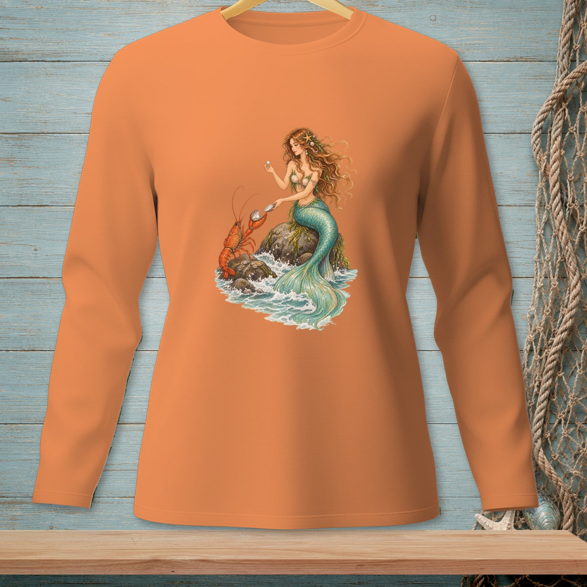 Orange long sleeve shirt with a mermaid holding pearls next to a lobster.