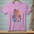 Two mermaids with purple and pink tails sit on a dock looking at a smartphone.