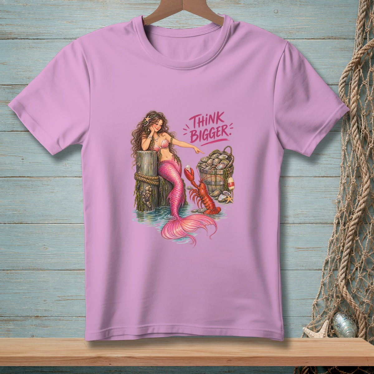 Pink t-shirt with mermaid, lobster, oyster bucket, and "THINK BIGGER" text.