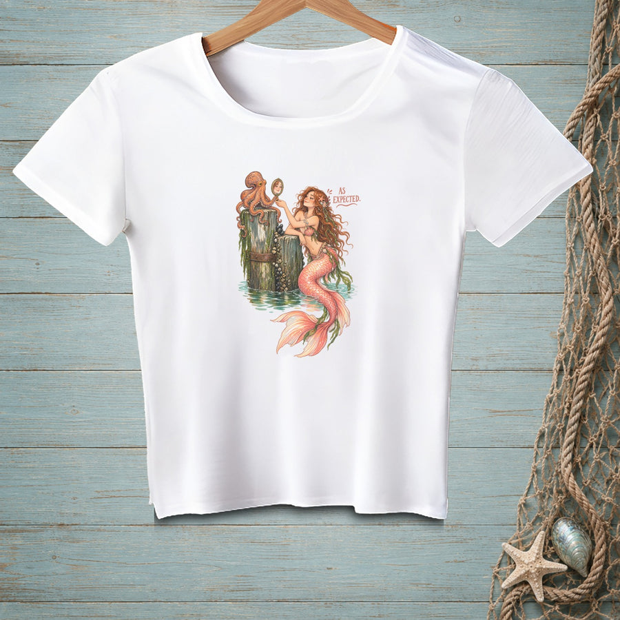 White t-shirt with illustration of mermaid and octopus looking in mirror, text "AS EXPECTED".