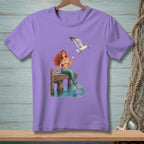Lavender t-shirt with a mermaid holding a drink near a seagull on a dock.