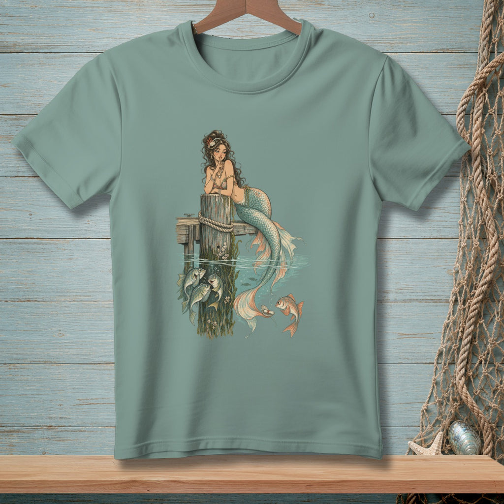 Mermaid leaning on a wooden post with fish in the water below.