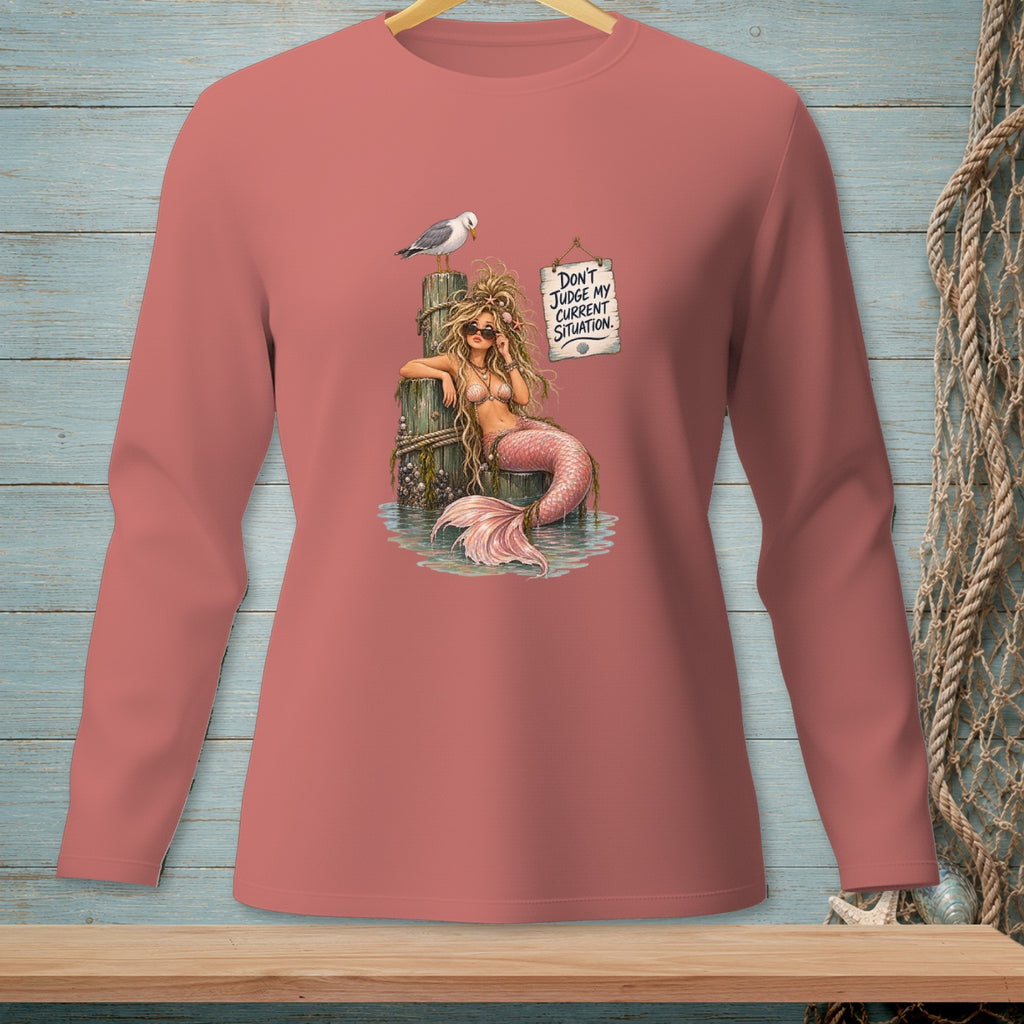 A mermaid sits on a wooden post with a seagull above, wearing sunglasses and a sign that reads "Don't judge my current situation."