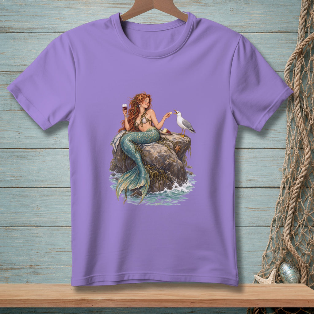 Purple t-shirt with mermaid holding wine, feeding a seagull on a rock.