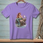 Purple t-shirt with mermaid holding wine, feeding a seagull on a rock.