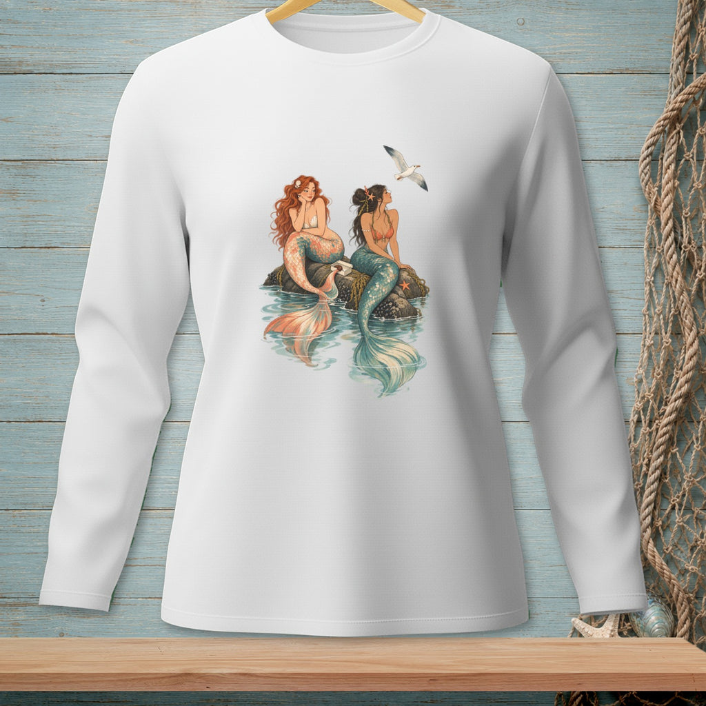 Two mermaids sit on rocks in the water, a seagull flies above.